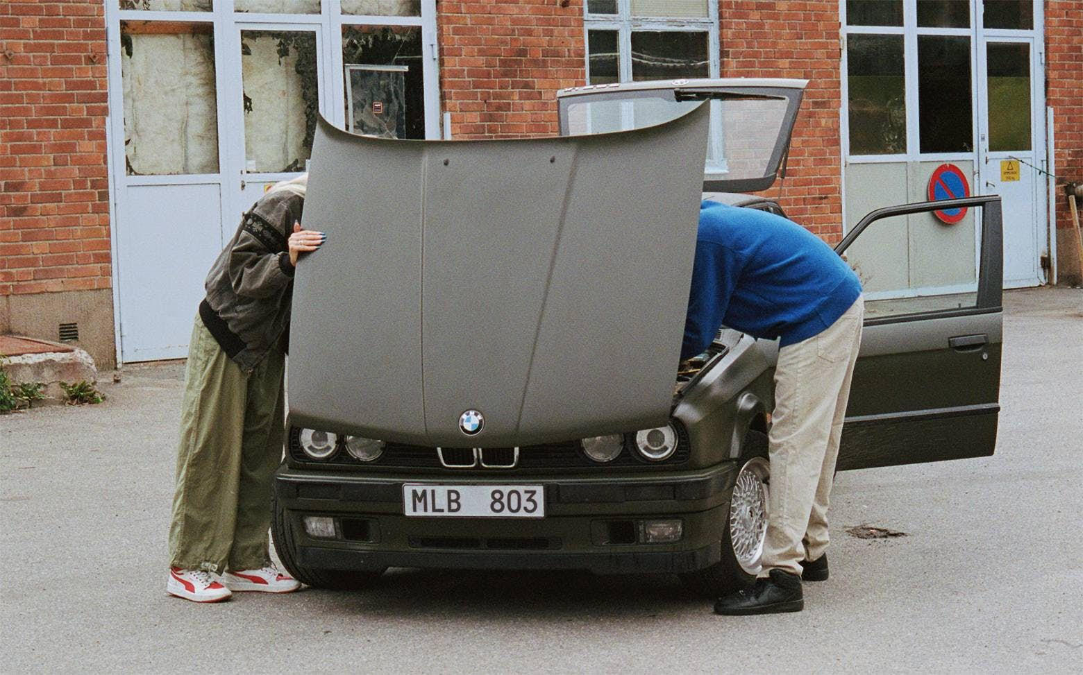 Två person tittar under motorhuven på bil med bilförsäkring.